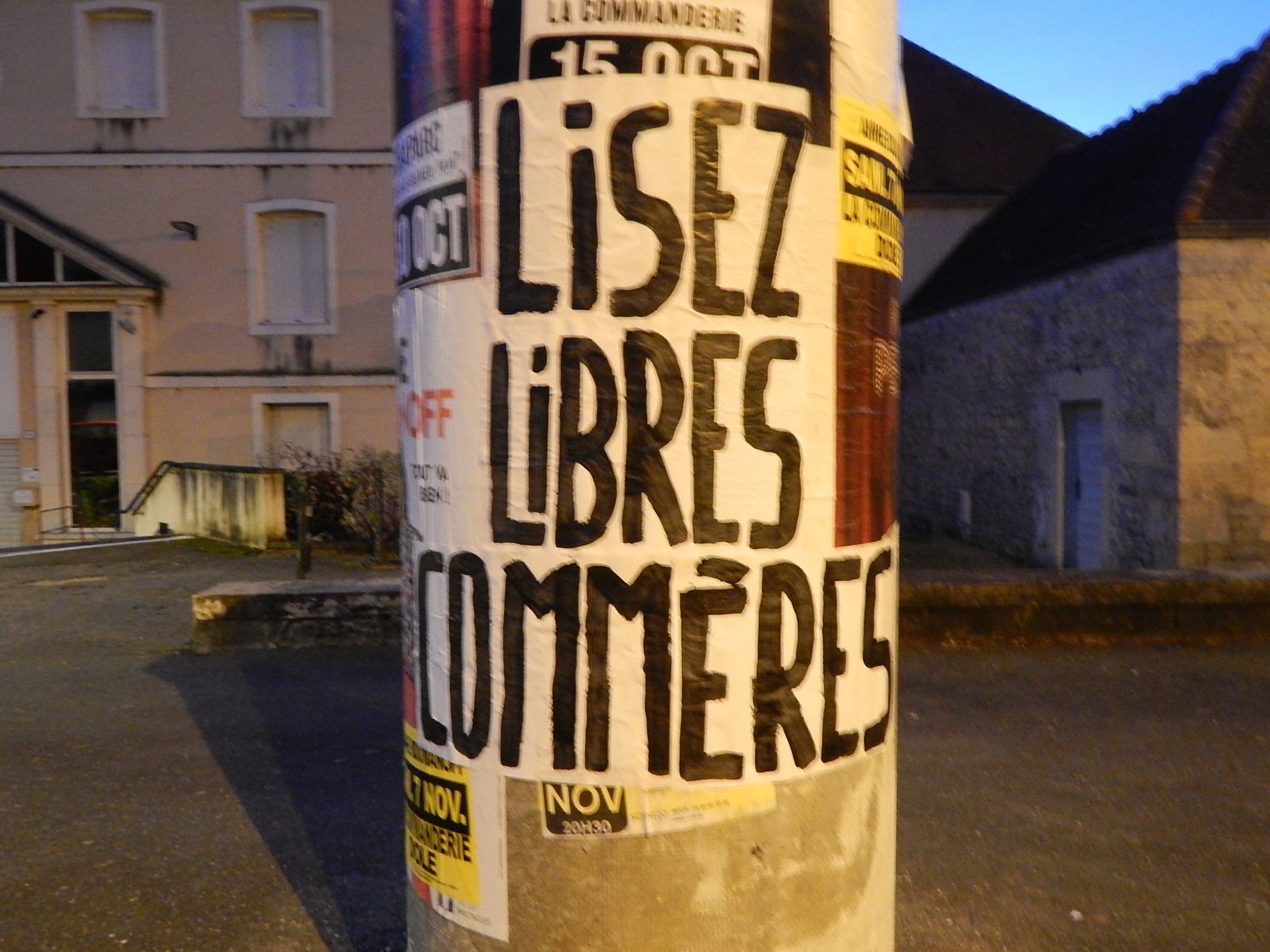 Image d'une affiche 'Lisez Libres Commères' collée sur une colonne maurice.